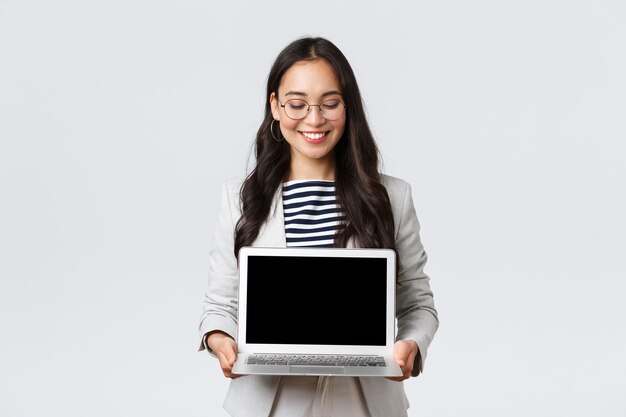 Business, finance and employment, female successful entrepreneurs concept. Enthusiastic businesswoman in suit and glasses showing presentation, demonstrate her project on laptop screen