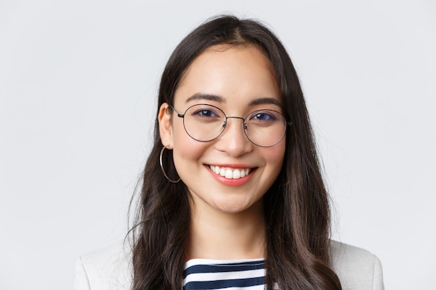 비즈니스, 금융 및 고용, 여성의 성공적인 기업가 개념. 안경을 쓴 잘 생긴 아시아 여성 사업가가 친절하고 자신감 있게 웃고 사무실에서 일합니다.