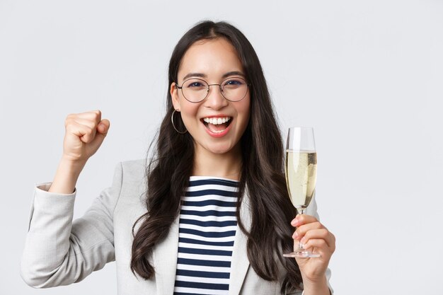 Business, finance and employment, female successful entrepreneurs concept. Happy asian businesswoman celebrating, having office party, drinking champagne, chanting from rejoice, triumphing
