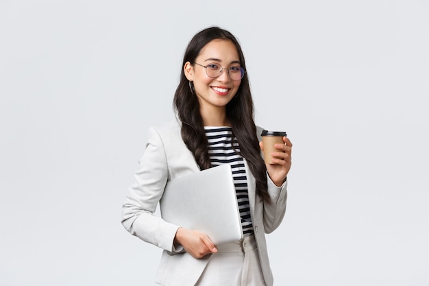 Free Photo business, finance and employment, female successful entrepreneurs concept. professional confident asian real estate broker drinking coffee and carry laptop, on her way to next client
