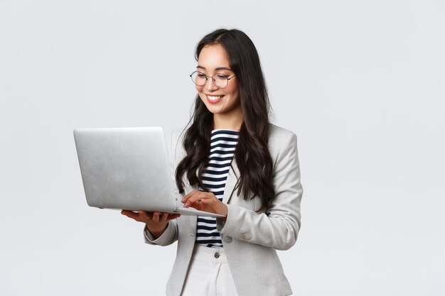 Business, finance and employment, female successful entrepreneurs concept. Professional stylish asian businesswoman fixing project on her way to office, using laptop standing whtie background