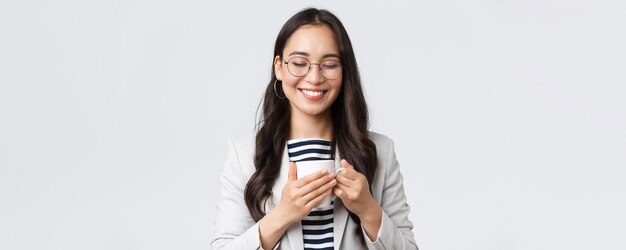 Business finance and employment female successful entrepreneurs concept Smiling happy asian businesswoman having coffee break hugging her favorite mug at office