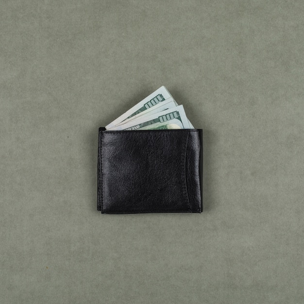 Business and financial concept with dollars in wallet on grey surface flat lay.