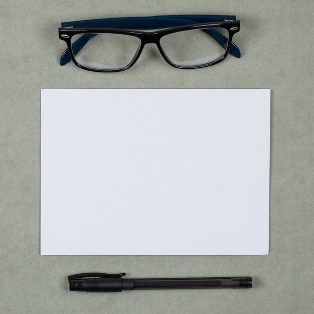 Business and financial concept with glasses, pen, blank paper on grey background flat lay.