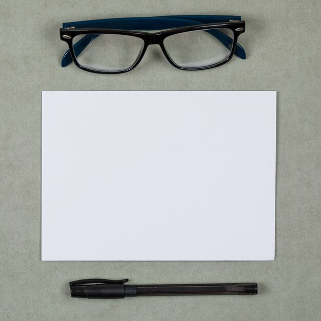 Деловая и финансовая концепция с очками, ручкой, чистым листом бумаги на сером второстепенном плоском положении.
