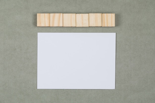 Бизнес и финансовые концепции с деревянными кубиками, чистый лист бумаги на сером фоне плоской планировки.