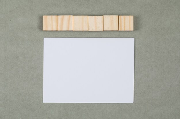 木製キューブ、平らな灰色の背景に白紙のビジネスと金融の概念を置きます。