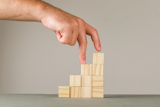 Business growth concept on grey and white wall side view. man putting fingers on step stairs.