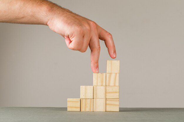 Business growth concept on grey and white wall side view. man putting fingers on step stairs.