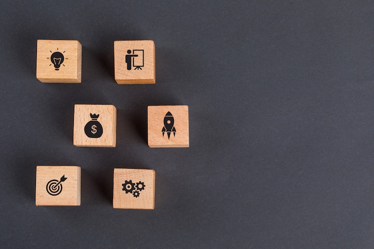 Free Photo business idea concept with icons on wooden cubes on dark grey table flat lay.