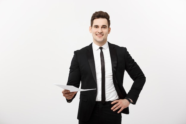 Бизнес и концепция работы: элегантный мужчина в костюме, держащий резюме для найма на работу в ярко-белом интерьере.