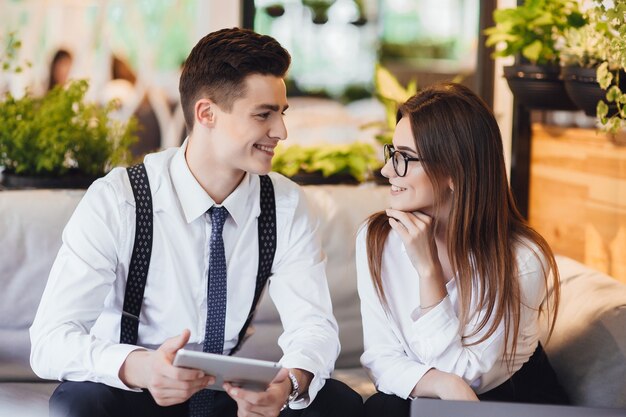 Business lunch! Two young people discuss a plan for a day in a cafe with a tablet