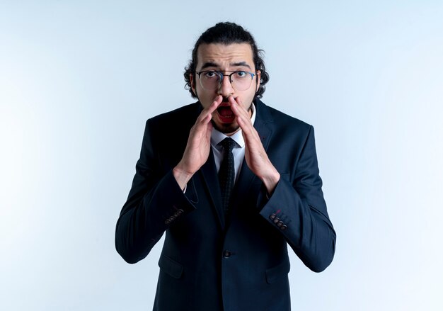 Free photo business man in black suit and glasses shouting or calling with hands near mouth standing over white wall