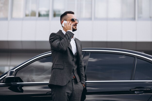 Business man by the car talking on the phone