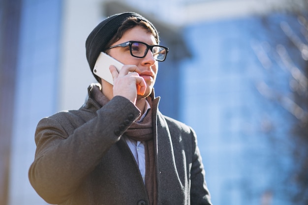 Business man by the skyscraper using phone