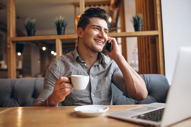 Business man in a cafe talking on the phone and drinking coffee