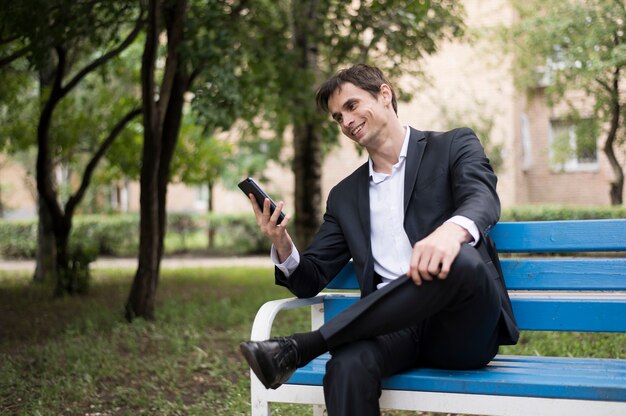 Business man checking his phone in park