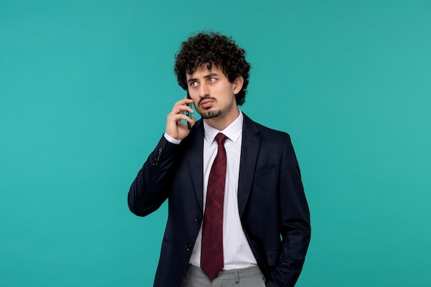 Business man curly cute handsome guy in black suit and red tie making a phone call with serious face