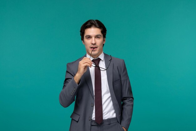 Business man cute young handsome man in grey office suit and tie biting corner of glasses