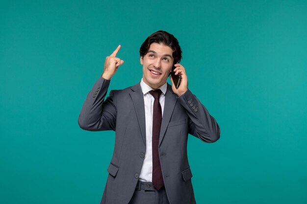 Business man cute young handsome man in grey office suit and tie pointing up on the phone