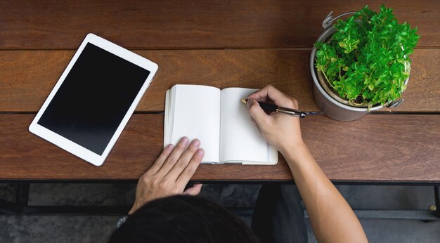 Деловая рука человека, используя ноутбук и писать заметку вдохновляют идею на деревянный стол, концепция запуска. вид сверху.