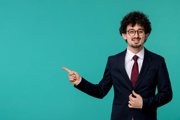 Business man handsome cute young guy in black suit and red tie wearing glasses and pointing left