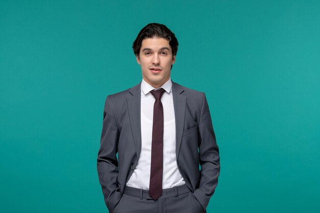 Деловой человек, красивый молодой брюнет в сером офисном костюме и галстуке, держащий руки в кармане