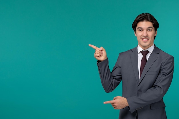 Деловой человек счастливый молодой милый красавец в сером офисном костюме и галстуке, указывая пальцами