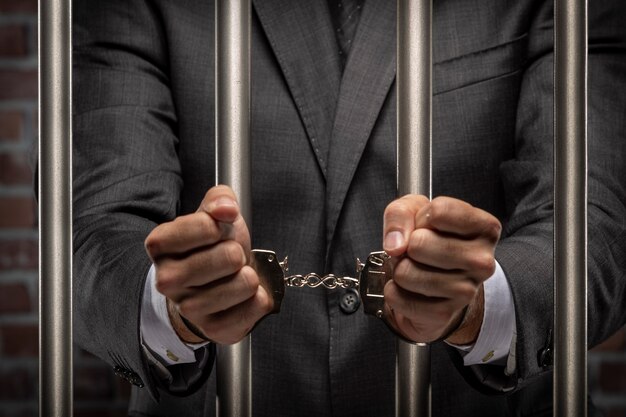 刑務所で手錠で紙幣を保持しているビジネスの男性 腐敗 腐敗した政治家 違法ビジネスの概念 レンガの背景 プレミアム写真