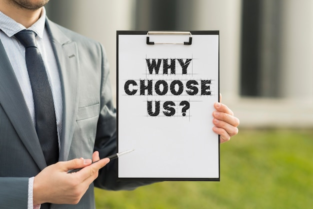 Free photo business man holding a clipboard with the why choose us question