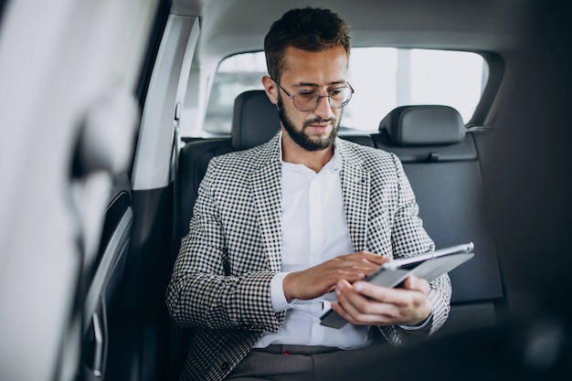 Uomo d'affari seduto sul sedile posteriore di un'auto utilizzando tablet