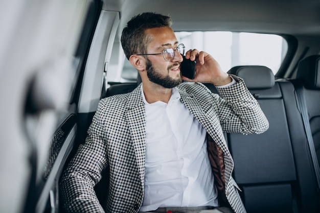 Free photo business man sitting on the back sit of a car using tablet