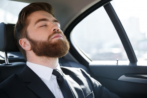 車の後部座席で寝ているビジネスマン