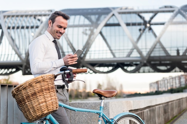 Деловой человек, стоящий у своего винтажного велосипеда и говорящий по мобильному телефону