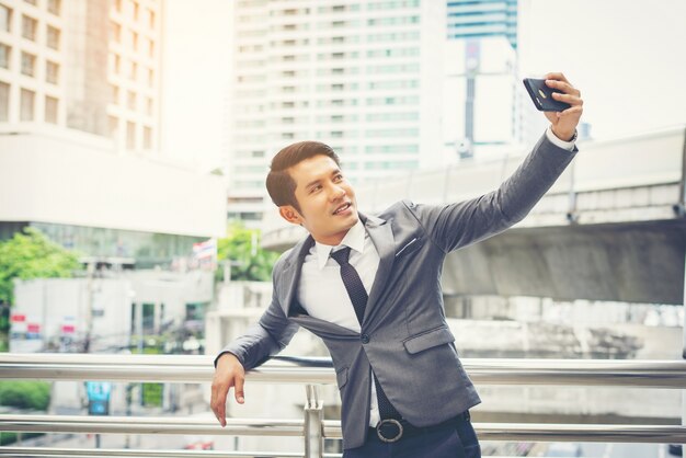 Business man taking selfie from phone outside.