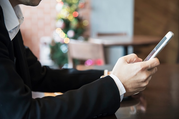 Uomo di affari che utilizza telefono cellulare mentre bevendo caffè in caffetteria