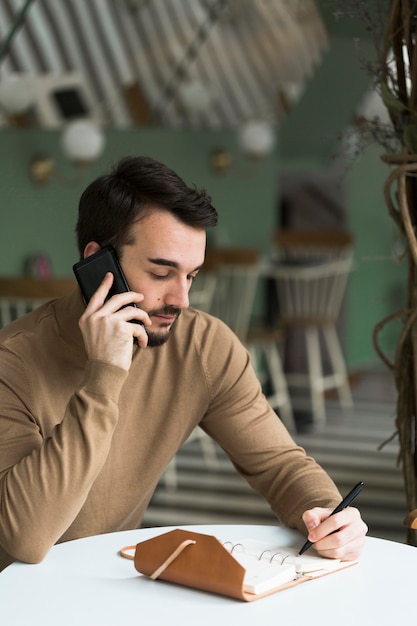 Uomo d'affari con agenda parlando al telefono