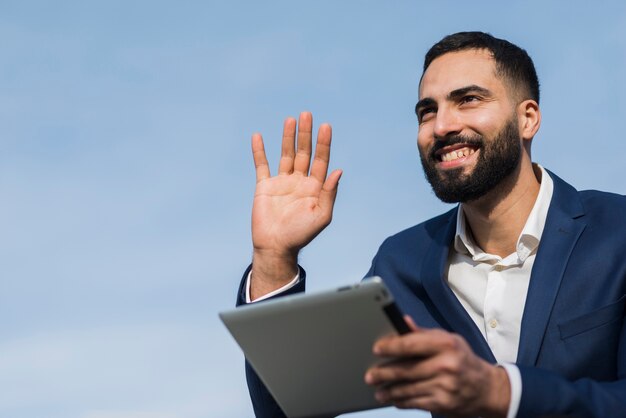 Business man with tablet waving