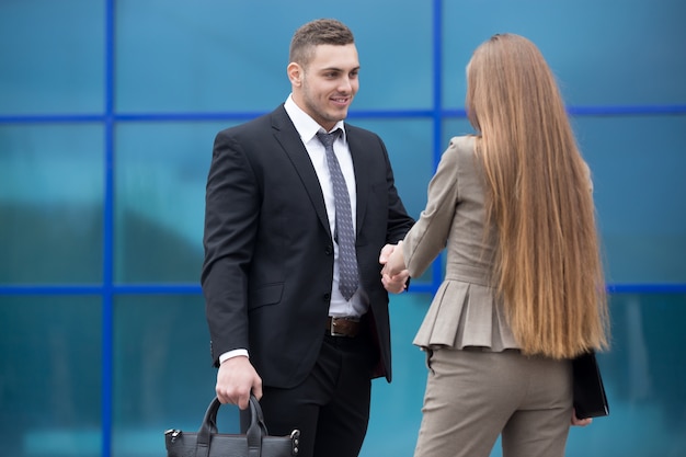 Business man and woman shaking hands on the street