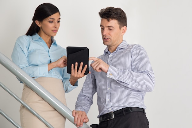 Бизнес-мужчина и женщина с помощью планшетного на лестнице