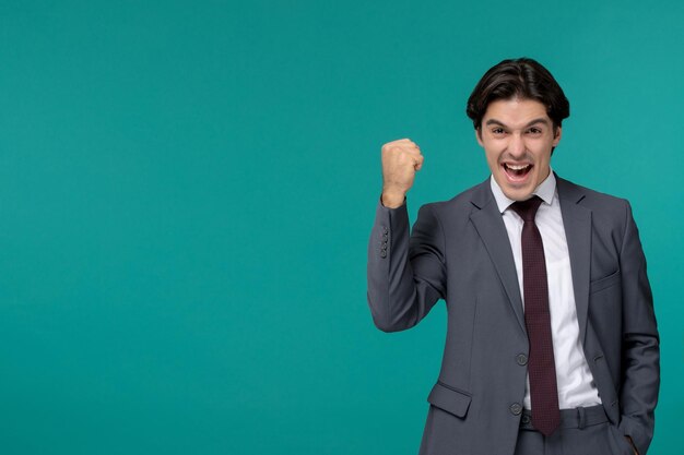 Business man young cute handsome man in grey office suit and tie holding fist up