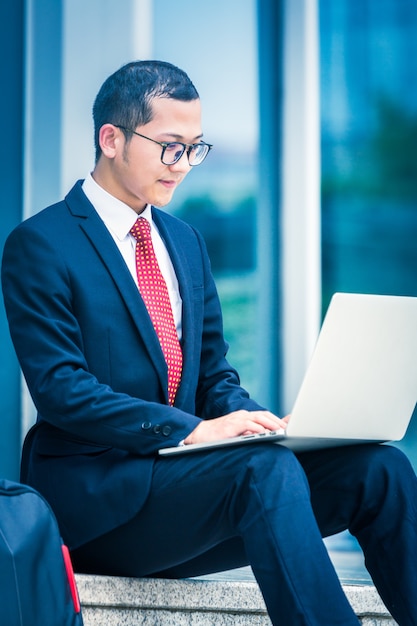 Business men use laptops at the entrance of an office building