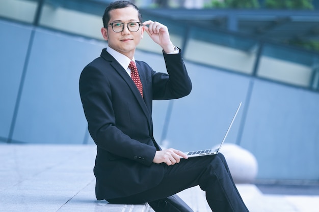 Free photo business men use laptops at the entrance of an office building