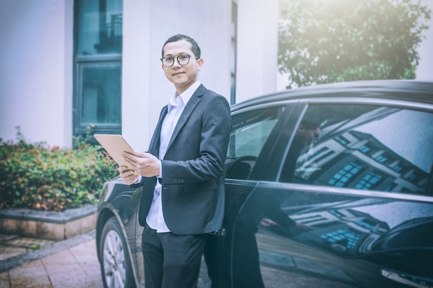 Free photo business men use tablet computers next to cars