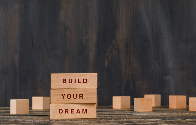 Business and motivation concept with wooden blocks on wooden table side view.