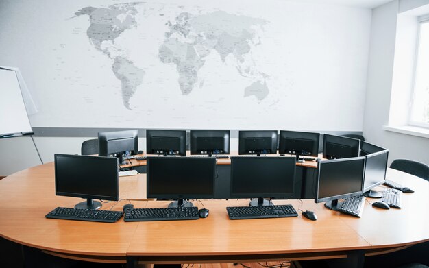 Business office at daytime with many computer screens. Map on the wall