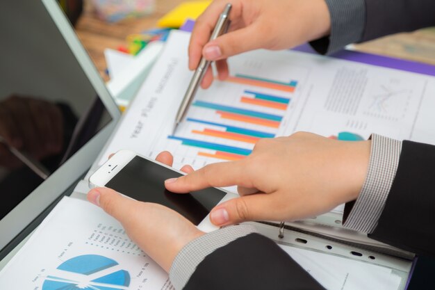 Free photo business people comparing results between a chart and a mobile