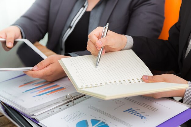 Business people comparing results on a tablet and a notebook