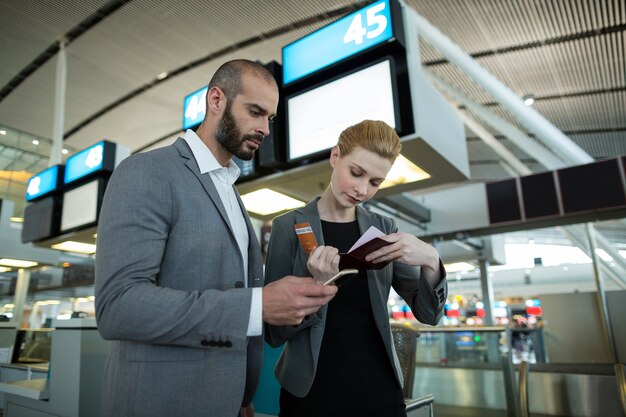 Business people holding boarding pass and using mobile phone