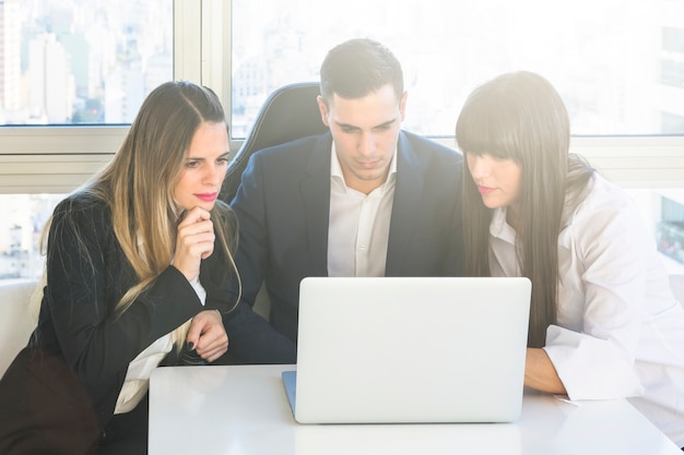 Gente di affari che esamina il computer portatile nella riunione